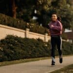 Young happy Asian sportswoman jogging on the street.